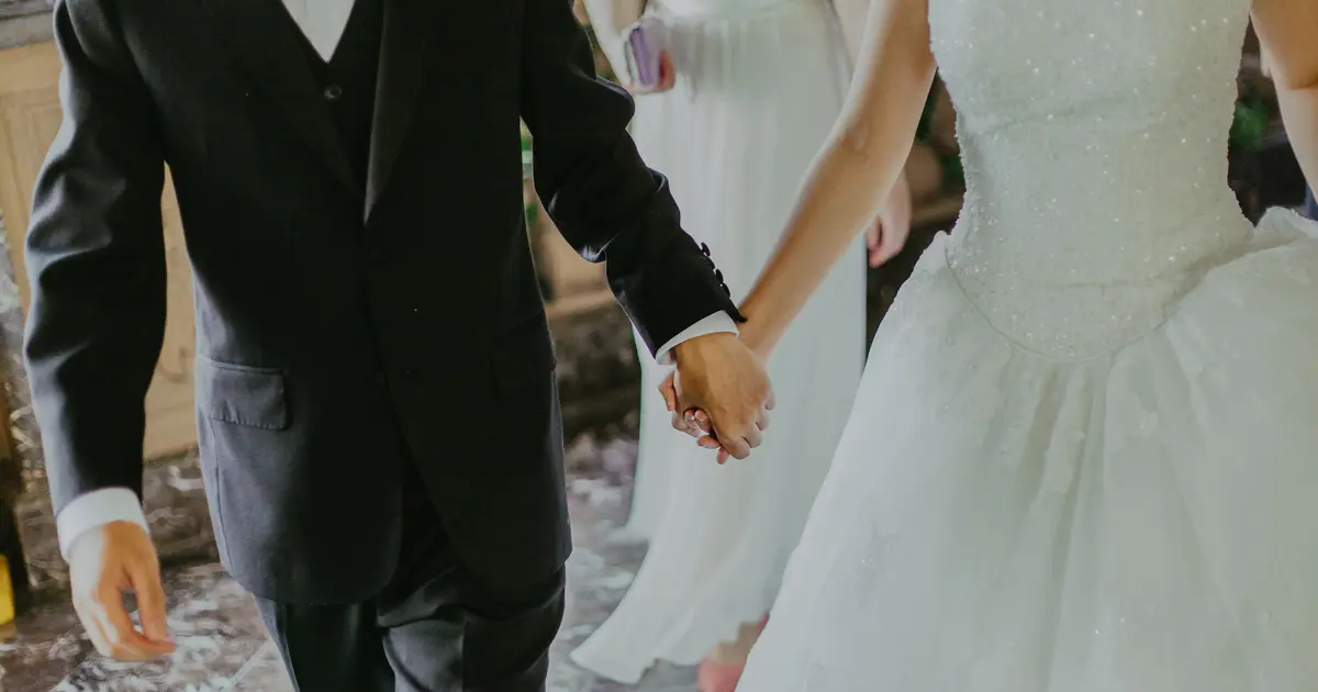 A couple holding hands during their marriage ceremony, both knowing they married the right person.