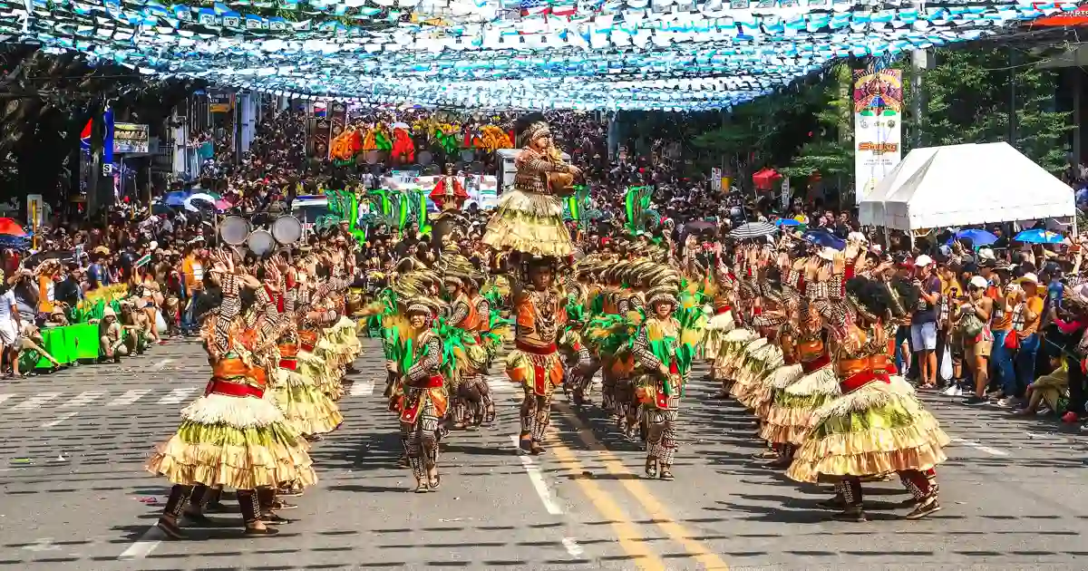 Dancers wearing tribal clothing and performing on the streets as part of a Filipino fest