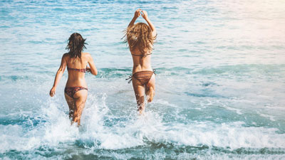 A photo of two women running towards the sea